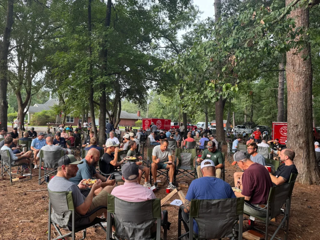 Red Truck Men gathering outdoors for fellowship beneath the trees